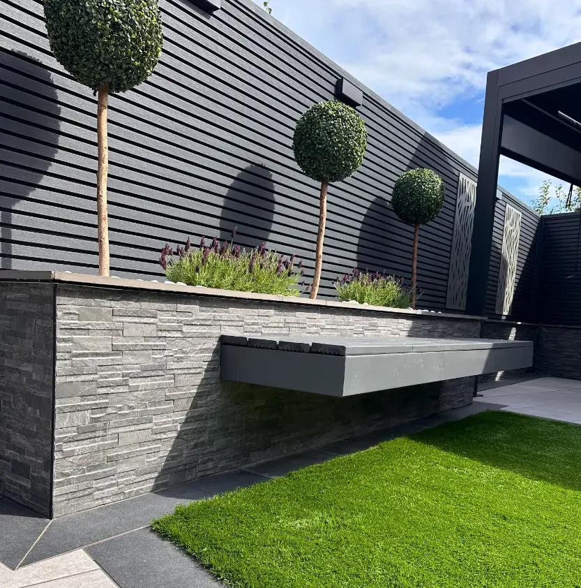 Modern garden design with split-face raised beds, porcelain coping and composite fencing installed in ashton in makerfeild by CG Paving Company.”